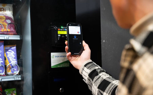 Bezoeker rekent contactloos af met de telefoon bij een automaat van DGA Vending