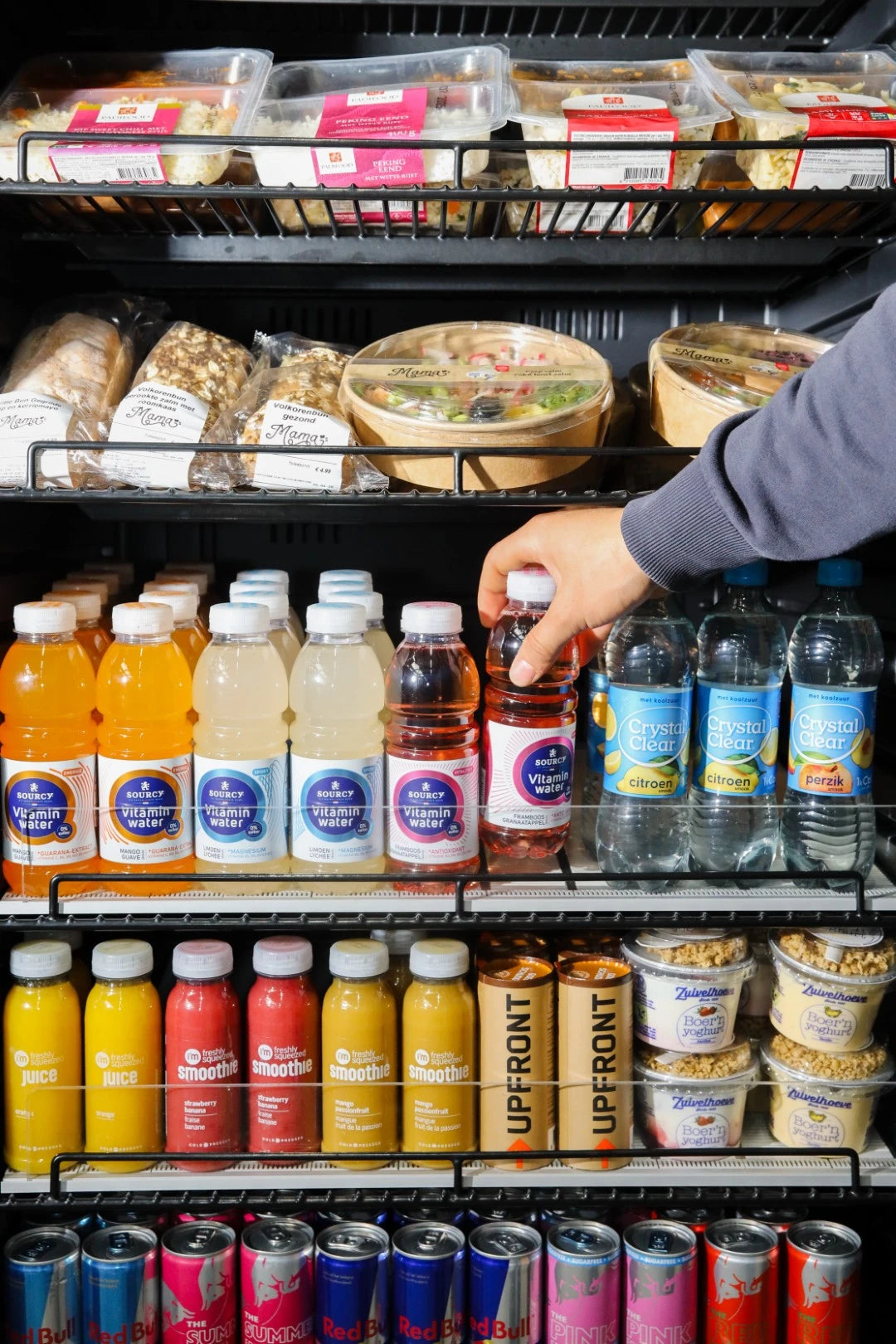 Een bezoeker kiest een drankje uit een automaat met verse broodjes en dranken