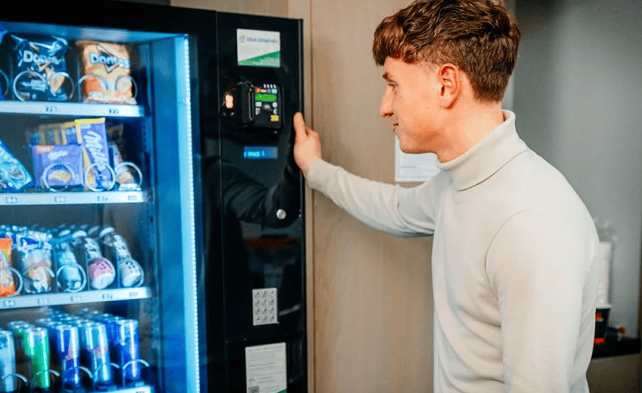 een vendingmachine met man die naar producten in de machine kijkt. - ein Verkaufsautomat mit einem Mann, der die Produkte im Automaten betrachtet | DGA Vending