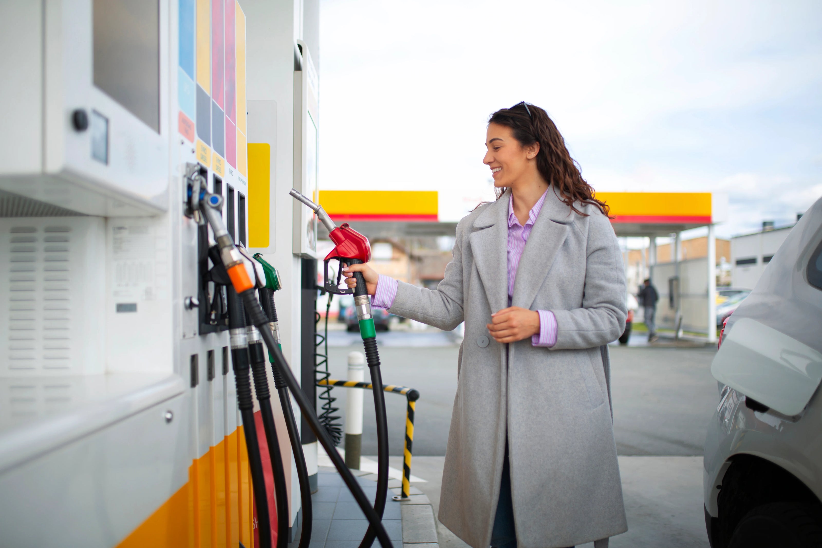 Vrouw-glimlacht-terwijl-ze-haar-auto-voltankt-bij-een-Shell-tankstation-een-alledaags-moment-waarop-gemak-en-service-centraal-staan-passend-bij-de-sectorgerichte-aanpak-van-DGA-Vending.