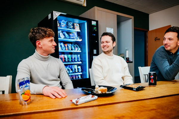 Collega's pakken snacks en drankjes bij een DGA-automaat in de bedrijfskantine