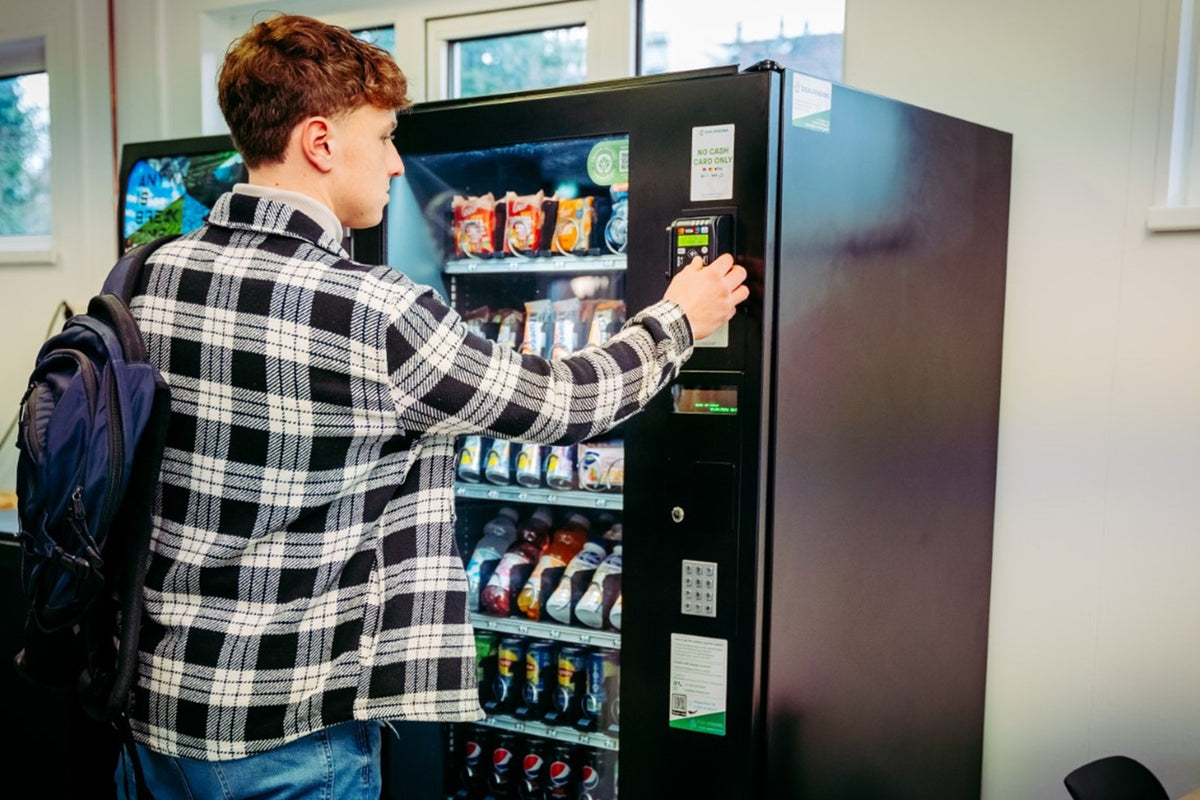 Student kiest een snack bij de DGA-automaat in de schoolkantine