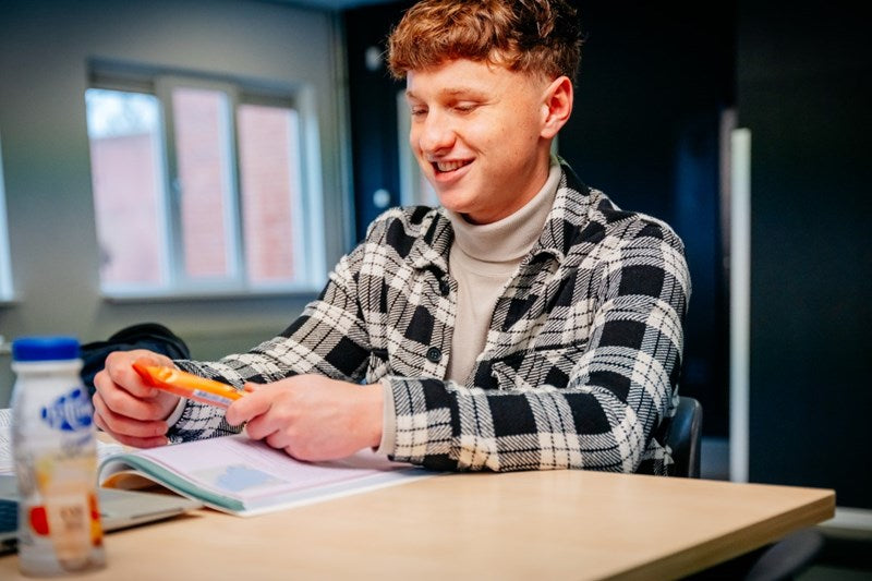 Student met een snack en een zuiveldrank uit de automaat aan zijn studietafel
