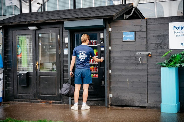 Sporter pakt een drankje bij de DGA-automaat naast de padelbaan