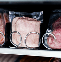 Vakuumverpackter Schinken und Hackfleisch in den Spiralfächern eines Fleischautomaten, Nahaufnahme